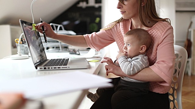 mother working from home while holding baby