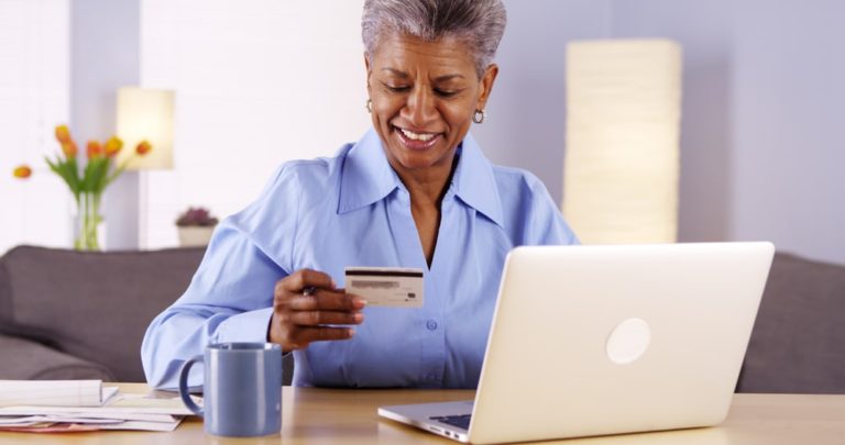 smiling lady using laptop w card in hand