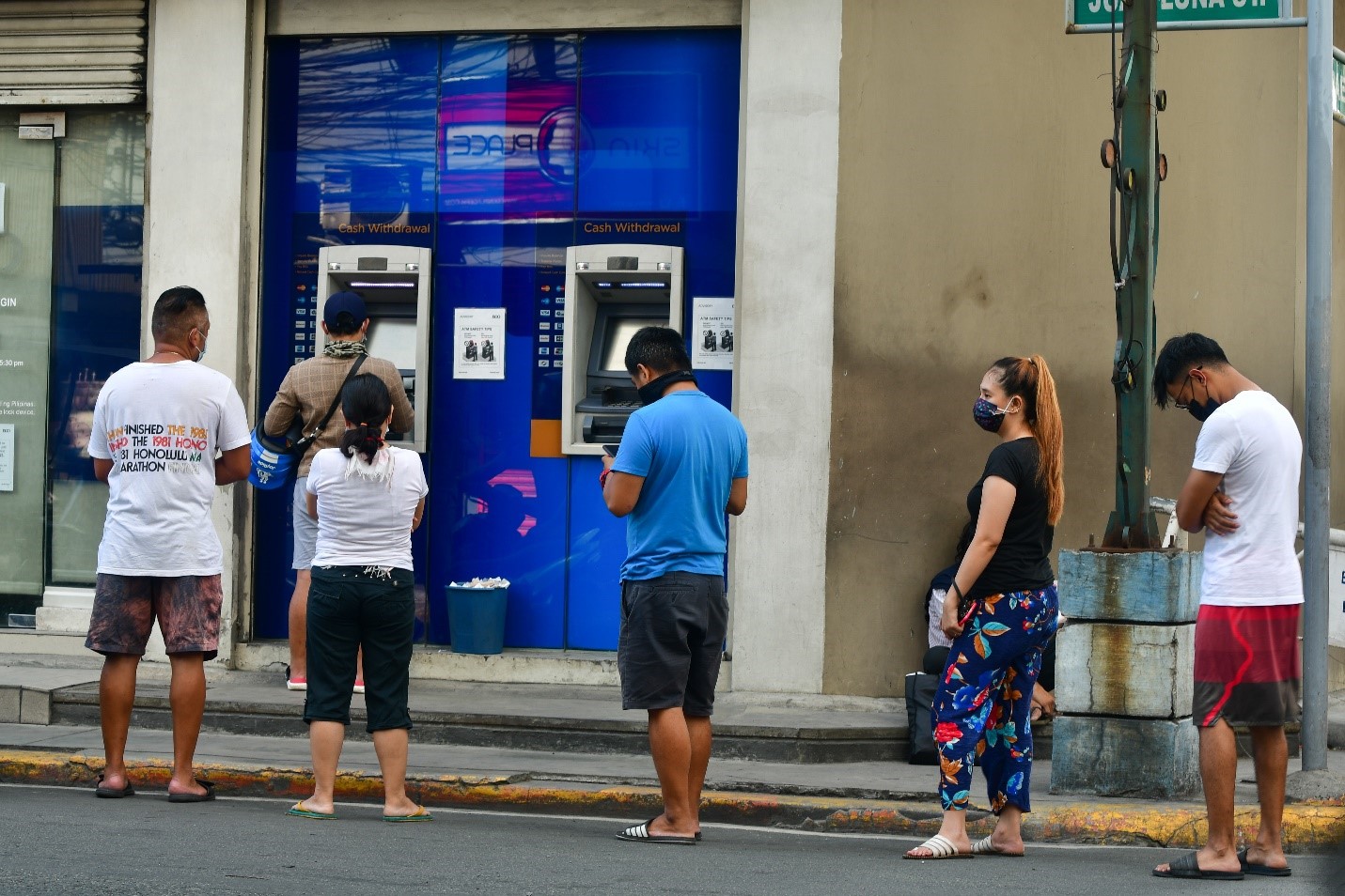 People lining up outside a bank's ATM