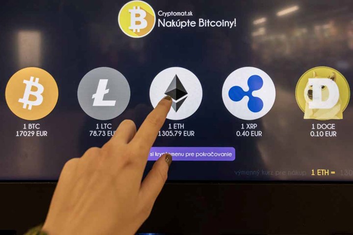 Fingers pointing to a screen showing various types of cryptocurrency