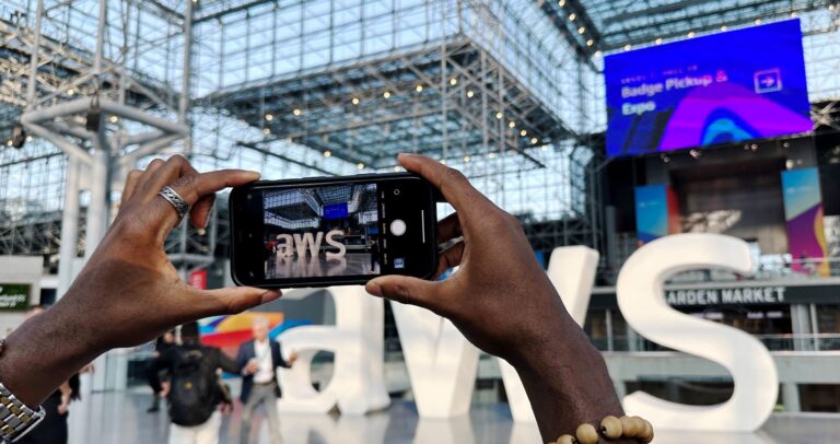 Two hands holding a mobile phone and taking pictures at AWS Summit NY