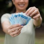 A woman holding a wad of Philippine money as Tala pushes for deeper digital financial inclusion beyond access for Filipinos, global majority