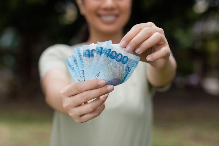 A woman holding a wad of Philippine money