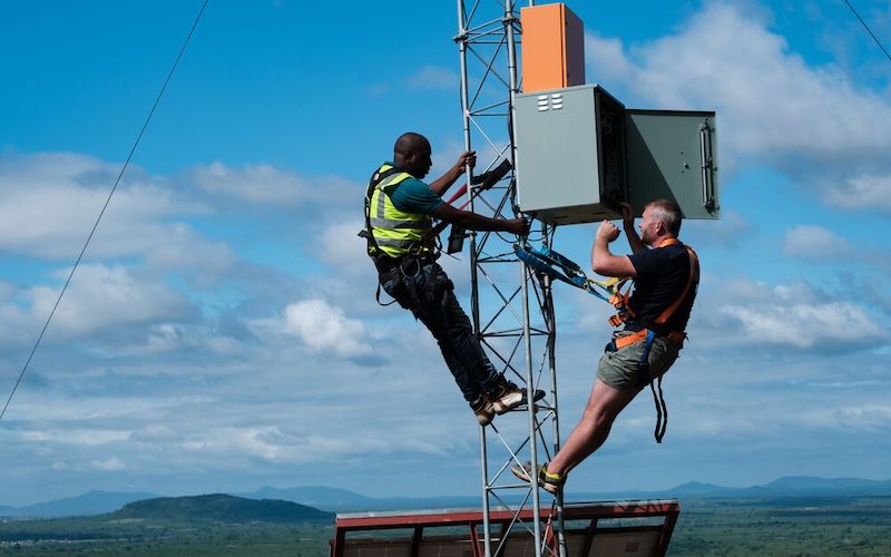 Two men climbing a tower to fix an Internet connection