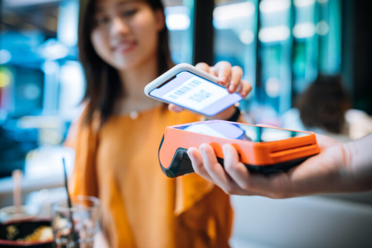 A girl using her mobile phone to make a payment transaction using QR codes