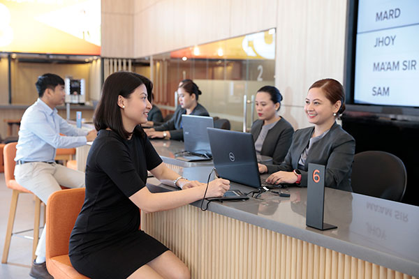 A female bank teller from UnionBank with a customer while using Red Hat OpenShift Service to service her needs