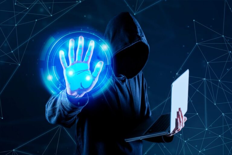 Man in hood holding a laptop with blue light in his right hand