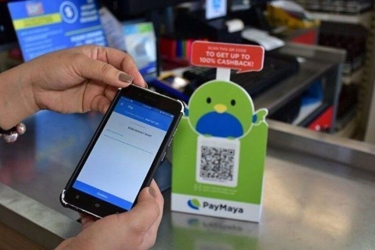 A woman holding a mobile phone as she completes an e-wallet transaction with PayMaya