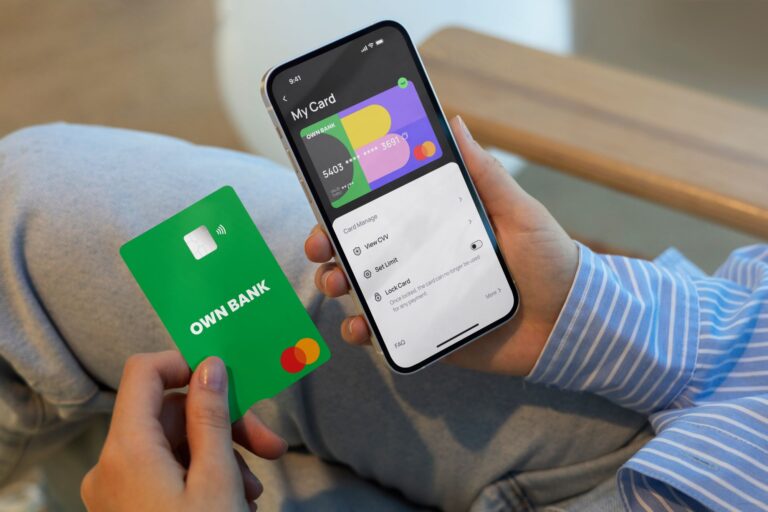 A person holding a mobile phone and OwnBank's digital debit card