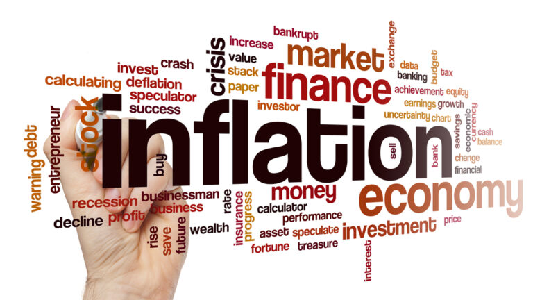 A hand with pen writing the words inflation, money, market finance and other economic terms