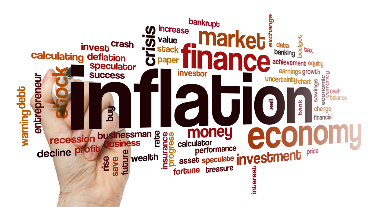A hand with pen writing the words inflation, money, market finance and other economic terms