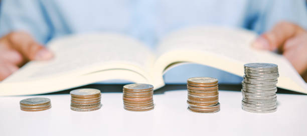 A Monetary Board photo showing a stack of coins and a man's hand holding a book as he studies the Balance of Payments