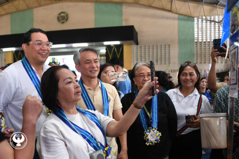 Former President and now Congresswoman Gloria Macapagal-Arroyo while scanning a QR code to pay for purchased goods during the launch of Paleng-QR Ph Plus in Guagua, Pampanga, which aims to aid in the municipality's digital transformation