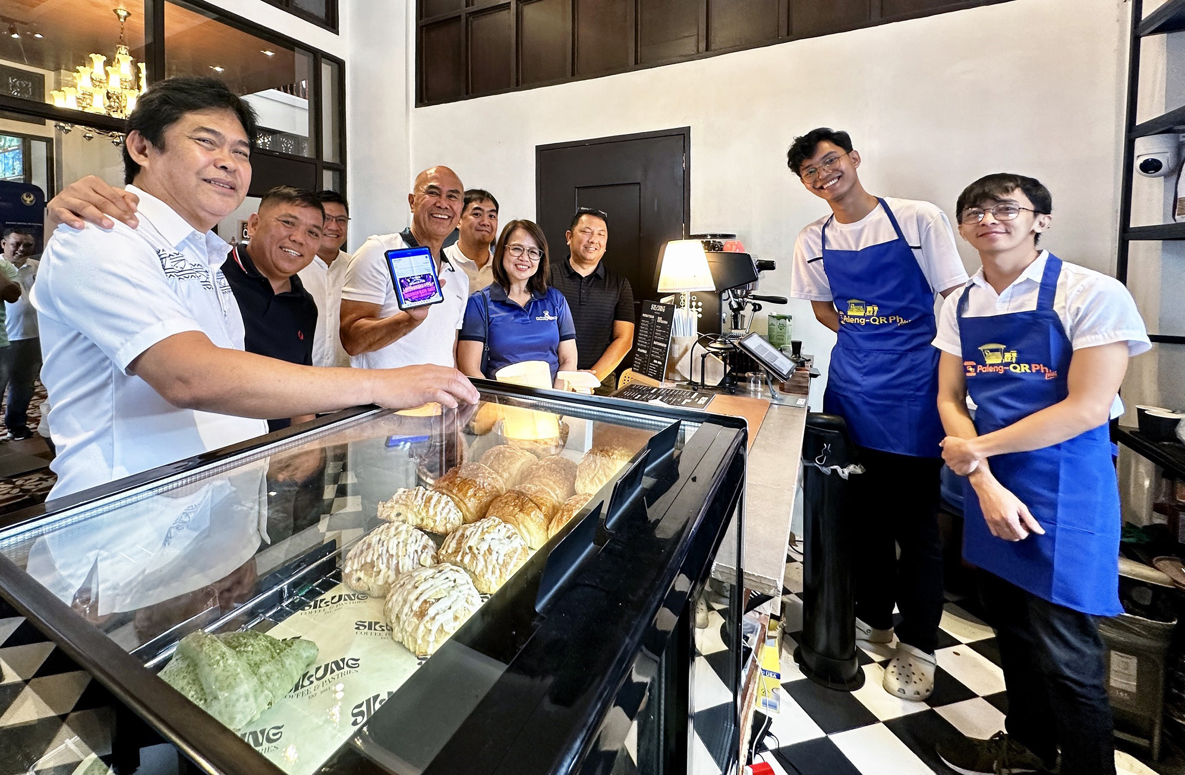 Photo shows BSP Managing Director Rosabel B. Guerrero (center) and Mabalacat City Mayor Crisostomo C. Garbo while showing e-payment proof at a café during the launch of Paleng-QR Ph Plus in Mabalacat, Pampanga