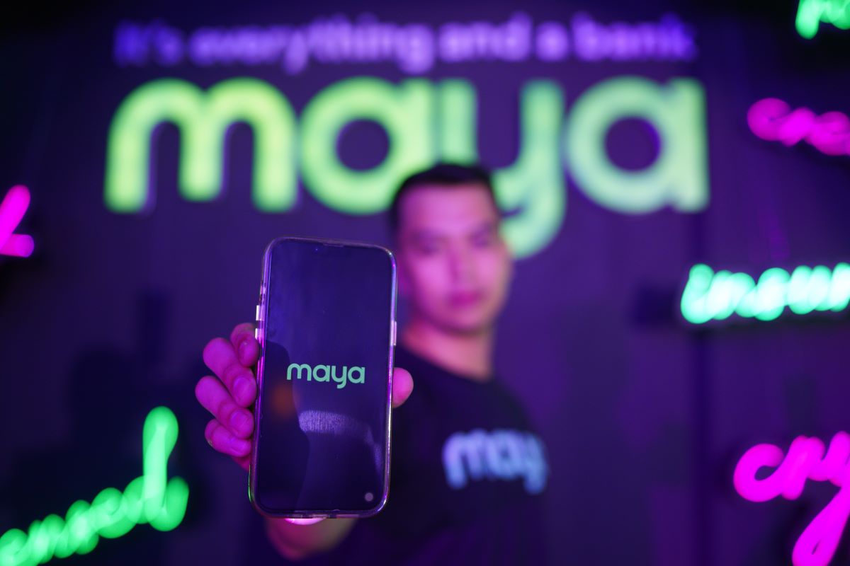 Man holding a mobile phone with the Maya Bank app