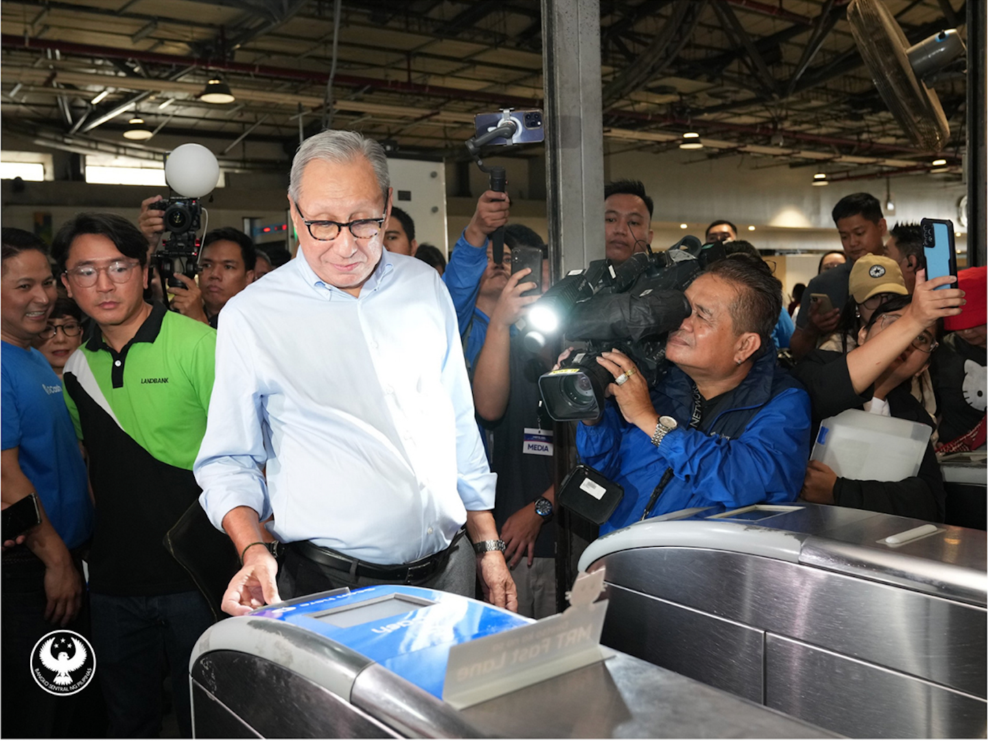 BSP Monetary Board Member Walter C. Wassmer pays train fares using a debit card to illustrate financial empowerment for train commuters