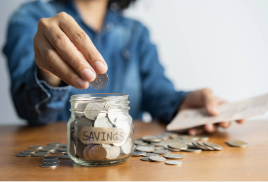 A girl putting coins in a jar as part of her financial journey goals