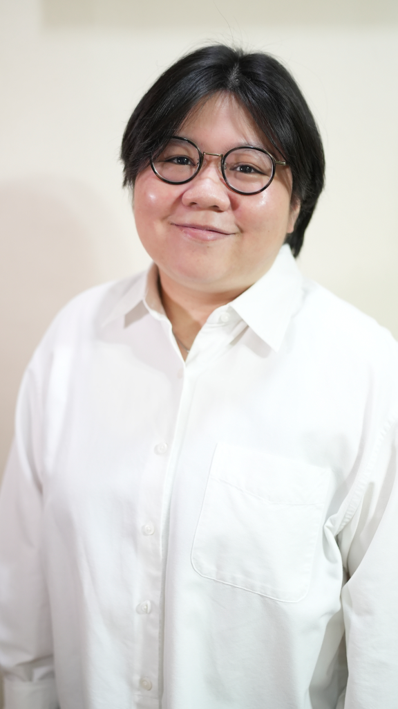 A woman with glasses wearing a white shirt, looking confidently at the camera.