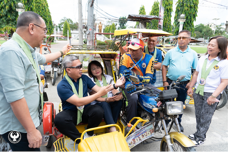 A BSP official, after giving the QR Ph explainer, pays a tricycle driver with GCash fees and Maya card guide