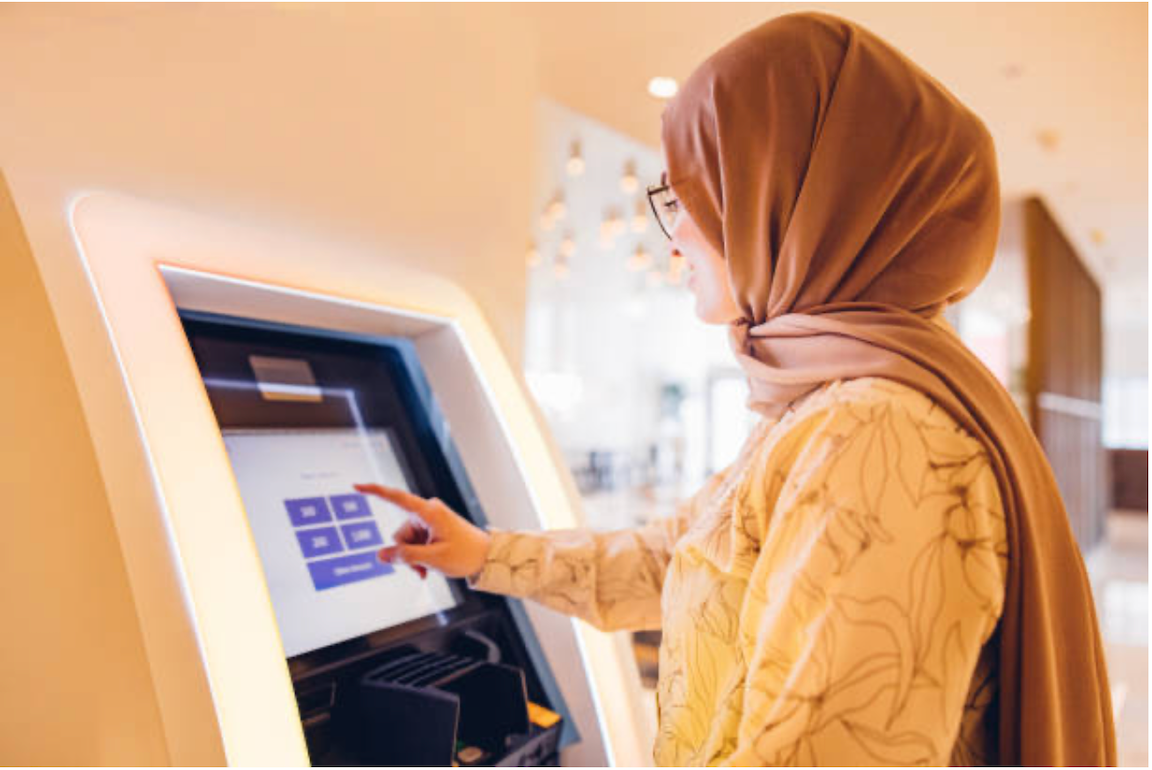 Image of a female traveler withdrawing cash from an ATM instead of a digital bank to demonstrate why we need financial inclusion
