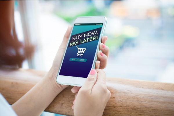 A handheld phone with the words "buy now pay later," a new term that could either be a lifeline or a shortcut to debt