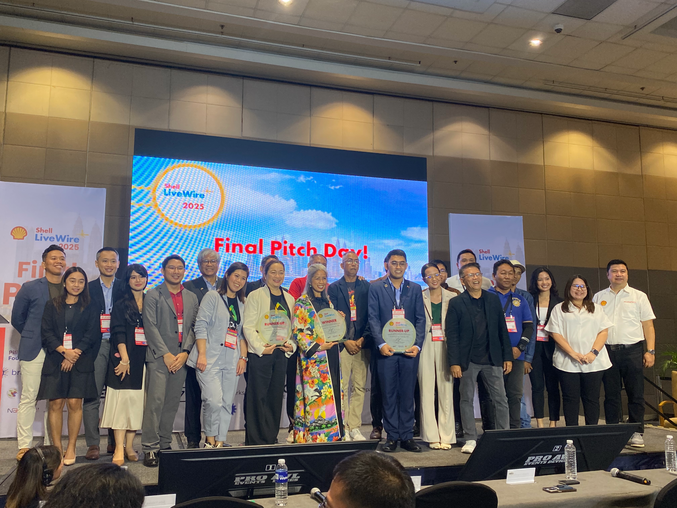 Group photo of Shell LiveWIRE 2025 Final Pitch Day finalists and organizers on stage.