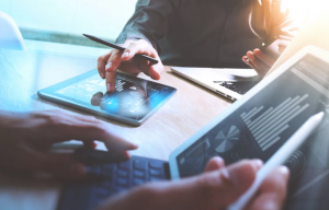 People using a tablet and a laptop to make digital finance transactions as audax joins AWS Partner Network