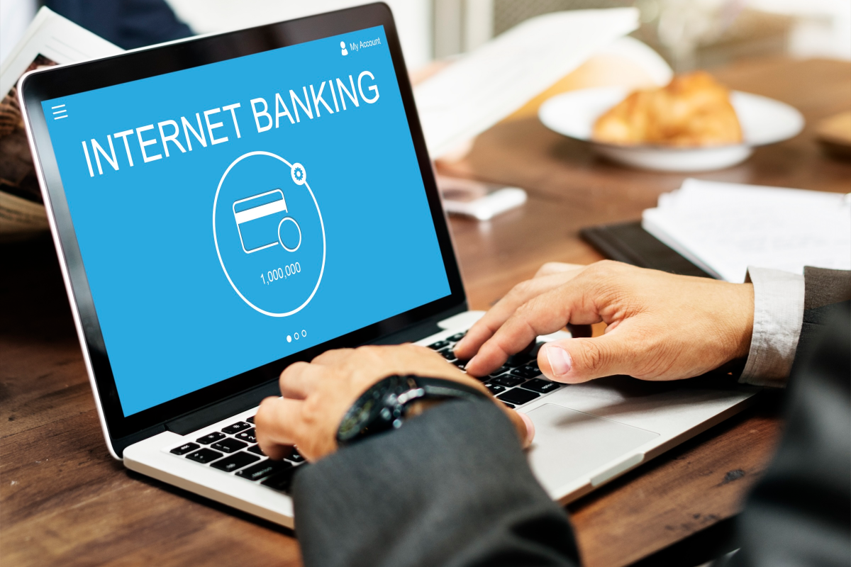 A man types on his laptop to do internet banking, showing how hard it is to balance bank automation with customer service expectations