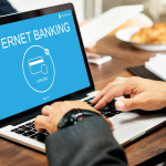 A man types on his laptop to do internet banking, showing how hard it is to balance bank automation with customer service expectations
