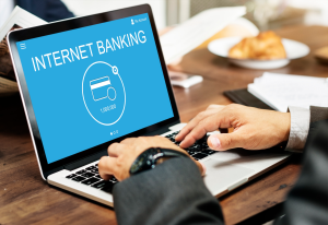 A man types on his laptop to do internet banking, showing how hard it is to balance bank automation with customer service expectations