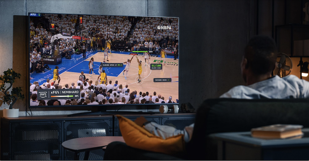 A man sits in front of his TV enjoying AI tech as the NBA partners with AWS