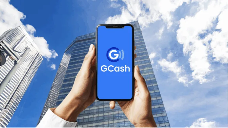 A man holds up his mobile phone amidst tall buildings in the background as GCash delays IPO to 2026 amid market volatility