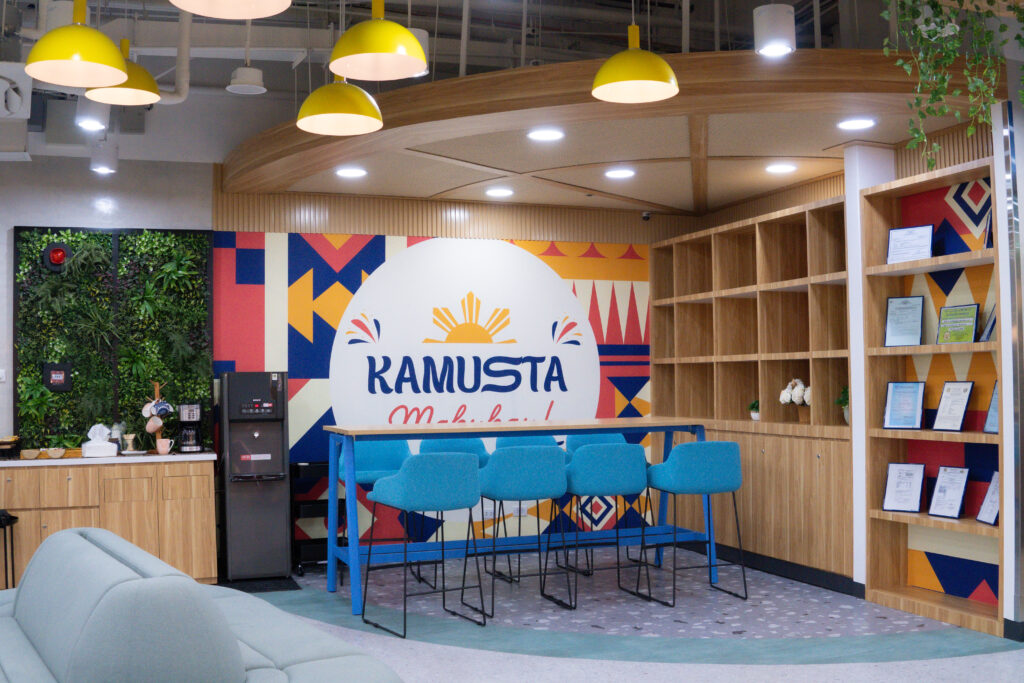 The “Kamusta, Mabuhay!” lounge area at TaskUs Hiraya showcases colorful Filipino-inspired wall art, bright seating, and a cozy space for employees to relax.
