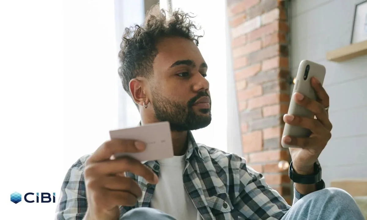 A young man holding a calling card and a mobile phone as he applies for a loan and heeds credit bureau CIBI, which is urging Pinoys to build credit early