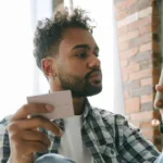 A young man holding a calling card and a mobile phone as he applies for a loan and heeds credit bureau CIBI, which is urging Pinoys to build credit early