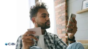 A young man holding a calling card and a mobile phone as he applies for a loan and heeds credit bureau CIBI, which is urging Pinoys to build credit early