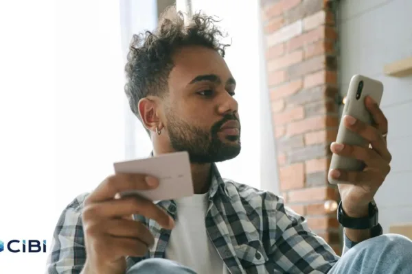 A young man holding a calling card and a mobile phone as he applies for a loan and heeds credit bureau CIBI, which is urging Pinoys to build credit early