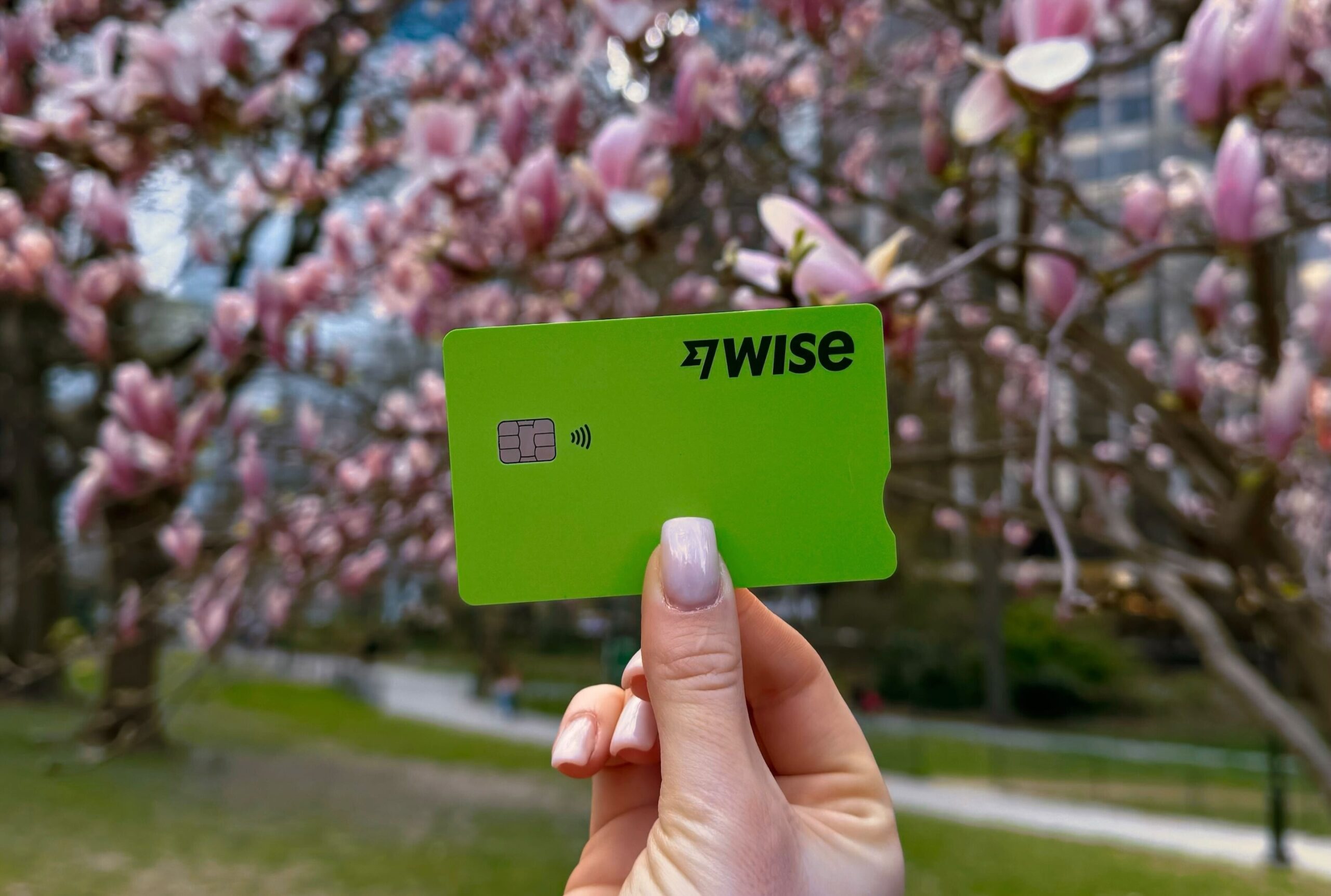 A person holding a green Wise card to help beat hidden ATM fees abroad