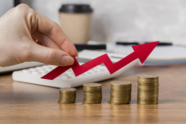 A hand holding arrow over coins to show how inflation is seen to stay within target range