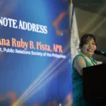PRSP President Ana Ruby B. Pista delivers a keynote address at DOST-TAPI’s 39th anniversary celebration, speaking at a podium with a backdrop displaying her name and title as President of the Public Relations Society of the Philippines.