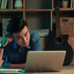 A man looks stressed while looking at his digital bank records may be a sign of digital fatigue