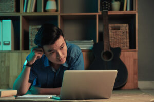 A man looks stressed while looking at his digital bank records may be a sign of digital fatigue