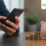 A person using a mobile banking app beside a piggy bank and stacked coins, symbolizing digital banking, savings, and modern financial habits.