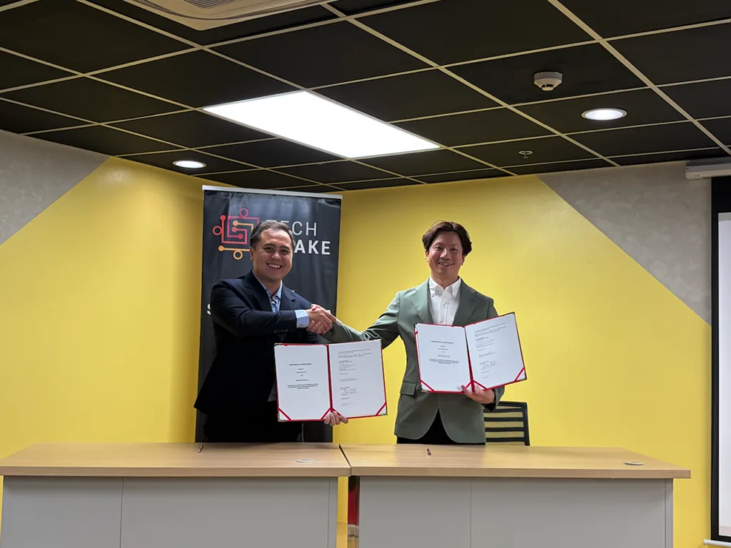 TechShake and Brunei Innovation Lab representatives shake hands while holding signed MOU documents during the partnership ceremony in Pasig City.